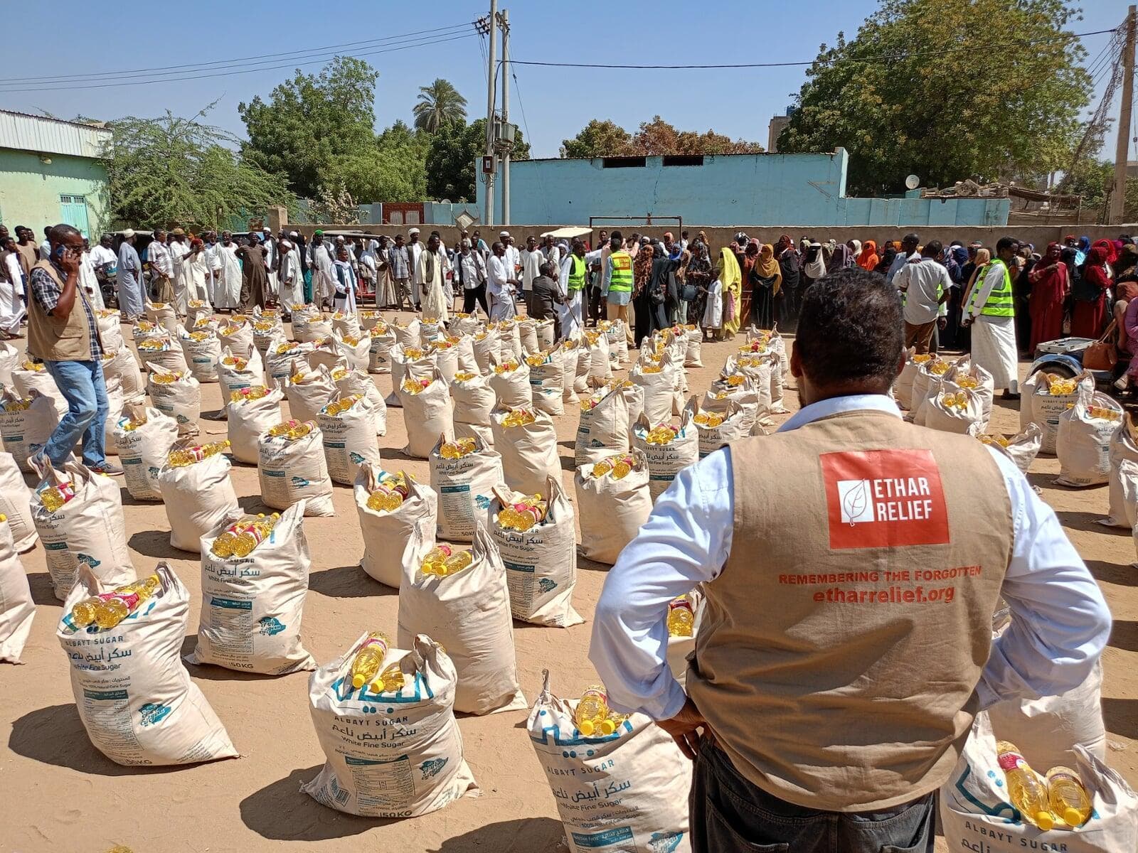 An Ethar team member beside food packs prepared for Ramadan distribution in Sudan.