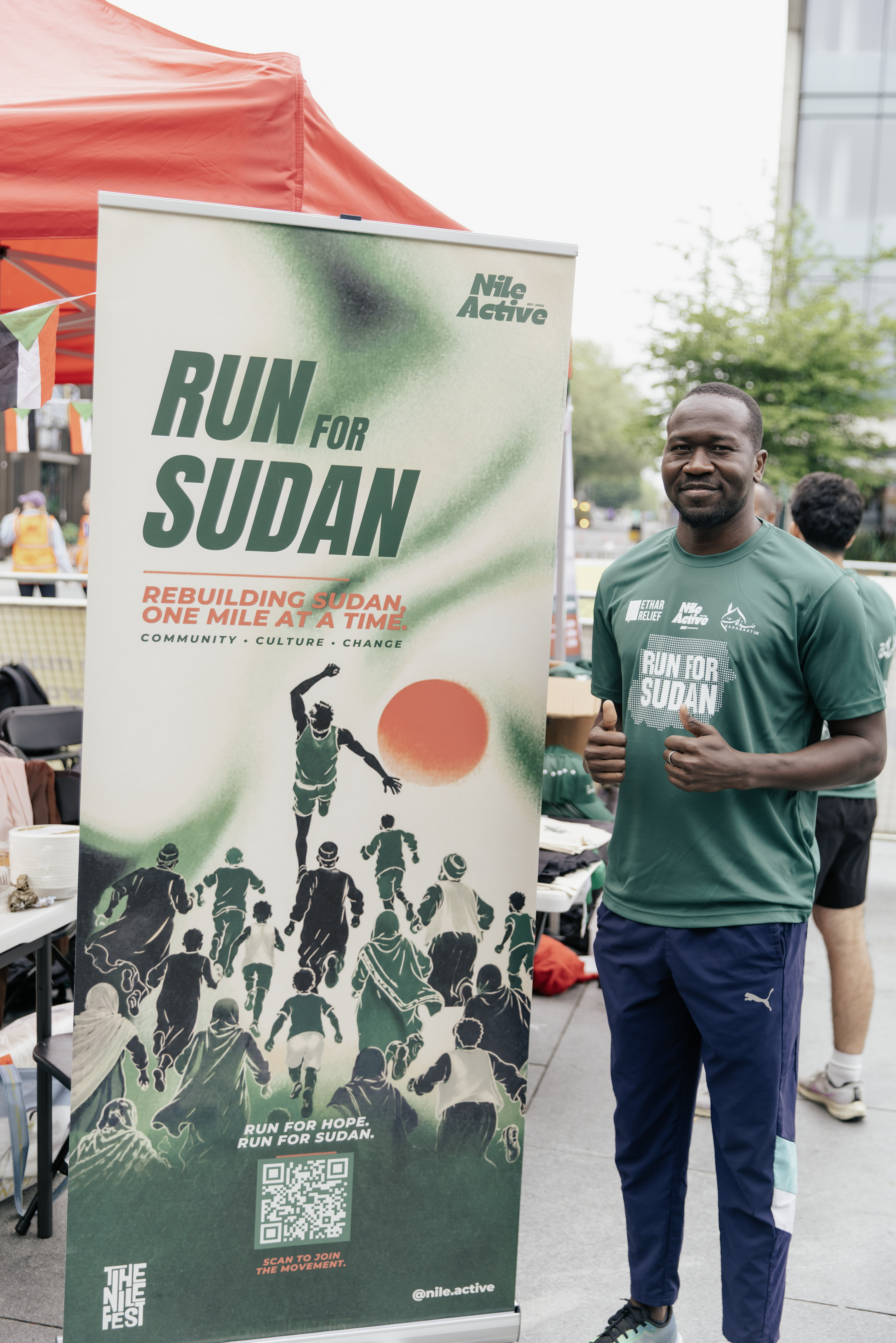 Run for Sudan athlete beside the campaign banner